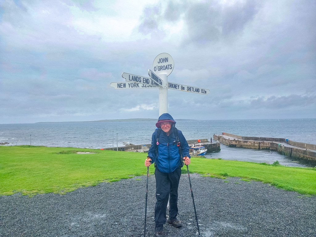 <center>2506-0122 - Chris at John o'Groats signpost -  June 23, 2025  <br>  (1/400 sec at f / 1.8 ISO 20    4 mm) </center>